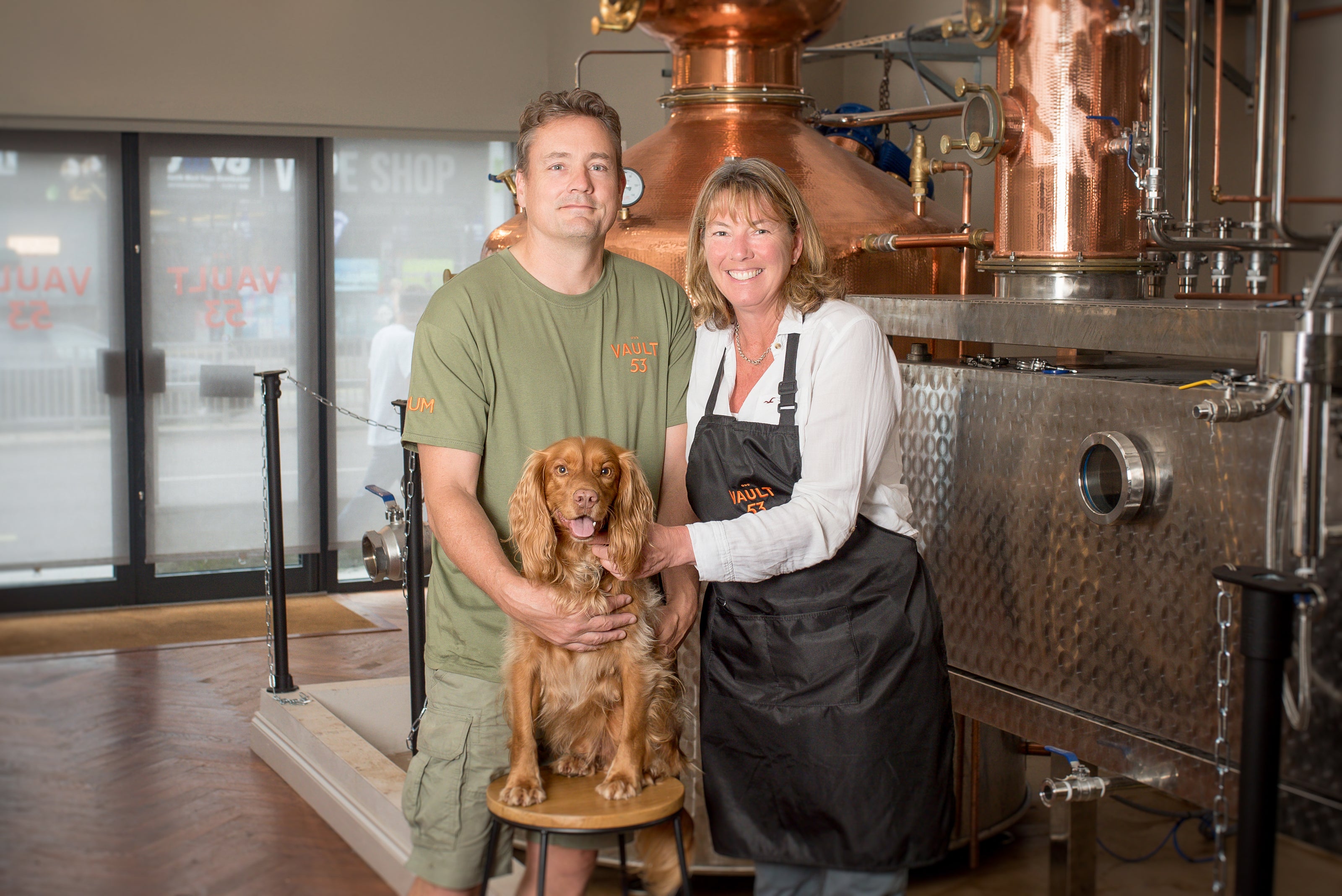 The owners of Vault 53 with their dog stood in front of a copper still