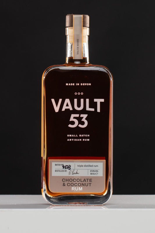 A bottle of Vault 53 Chocolate and Coconut Rum with a dark label and a clear view of the infused rum inside.