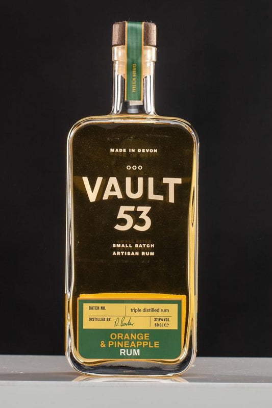 A bottle of Vault 53 Orange and Pineapple Rum with a clear label displaying the product name and fruit flavors, set against a dark background.