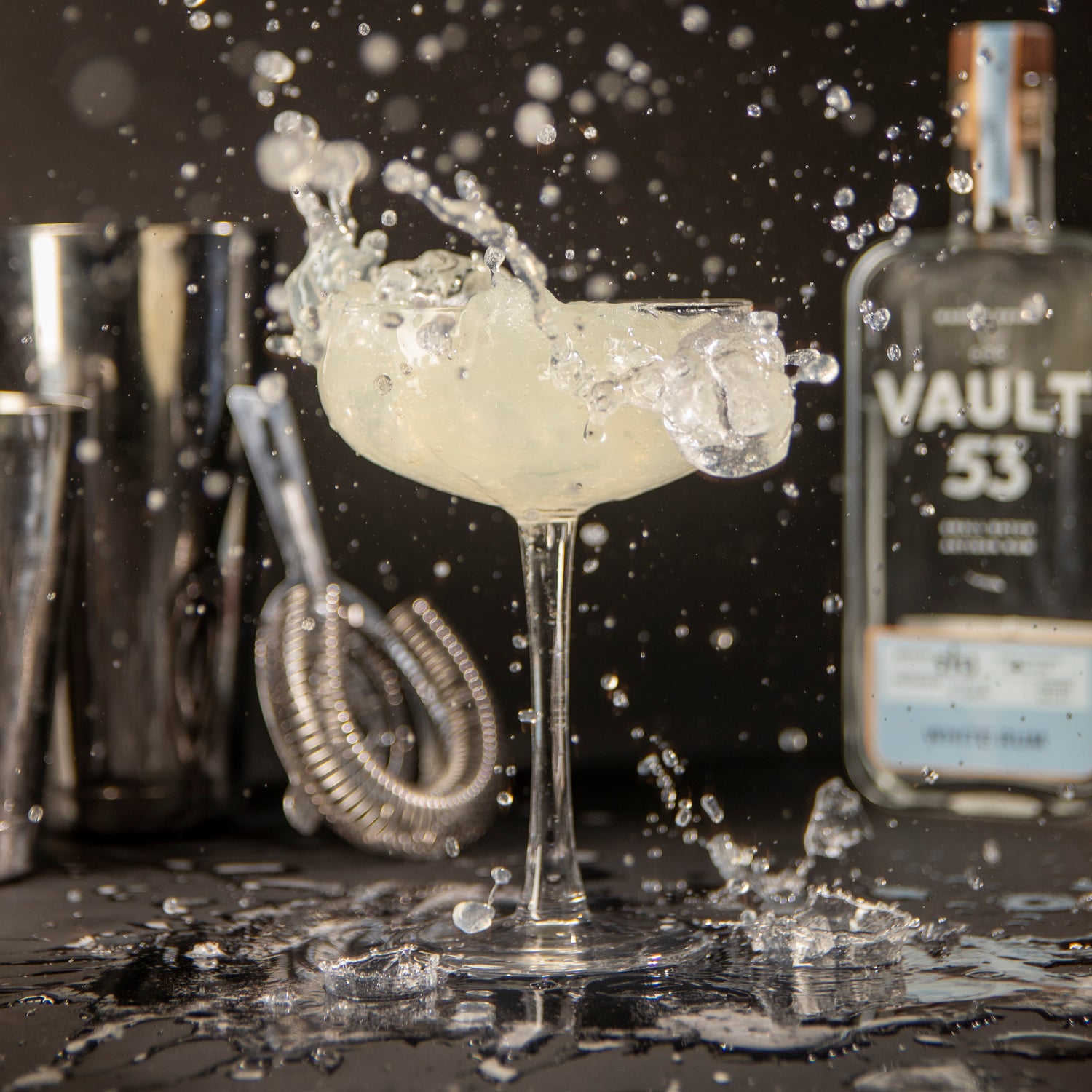 Cocktail being poured with 'Vault 53' bottle in the background